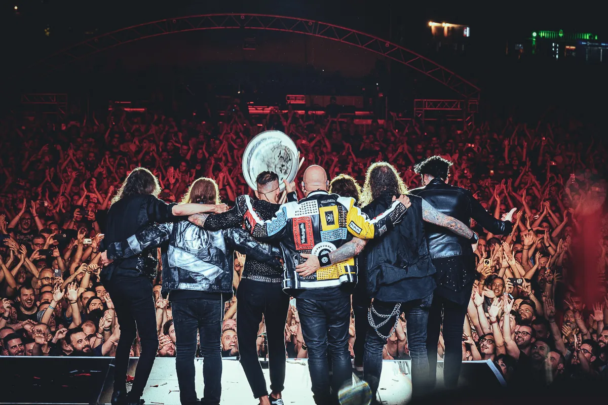 Band arm in arm on stage, facing a cheering festival crowd