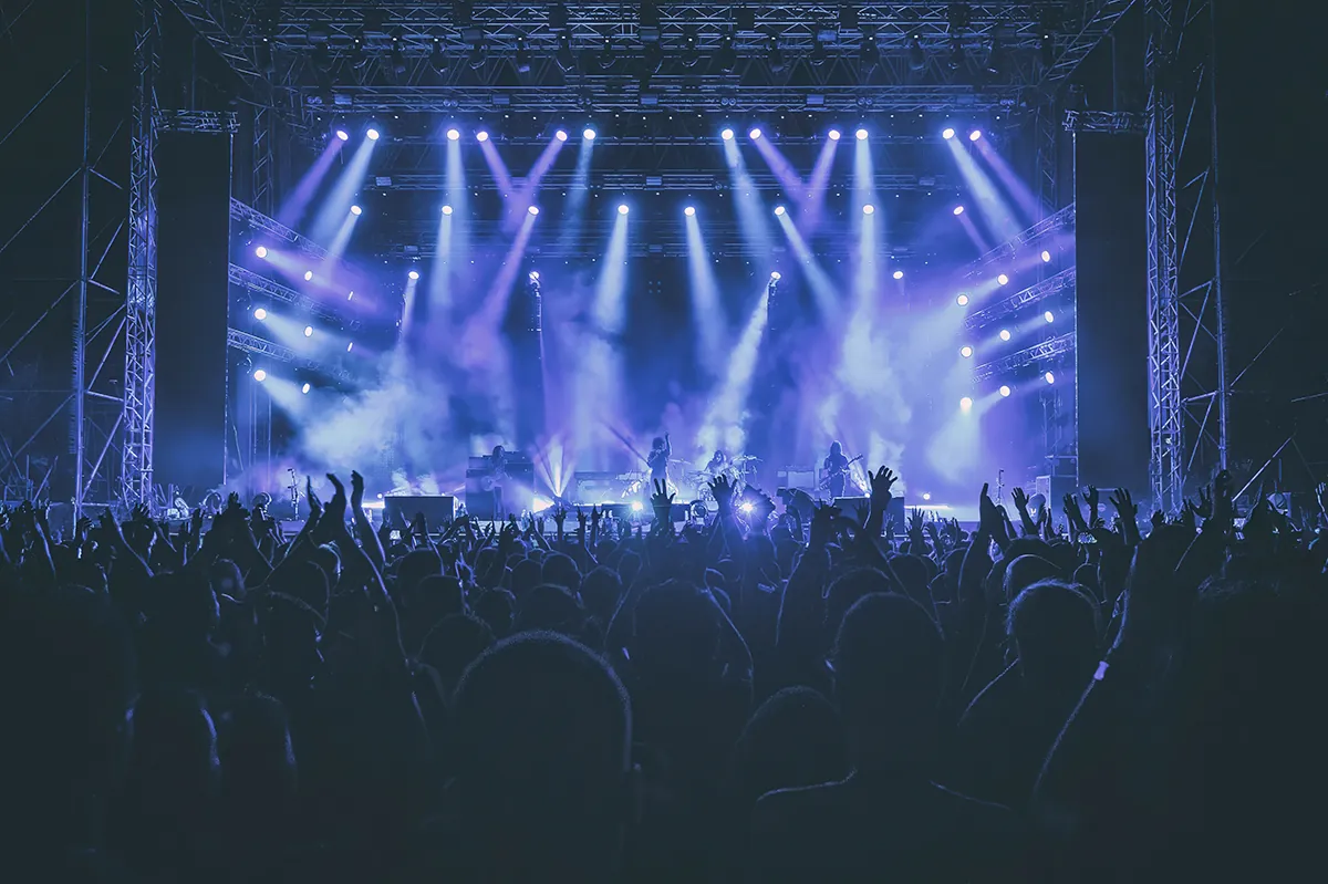 Crowd with raised hands in front of a stage in blue light