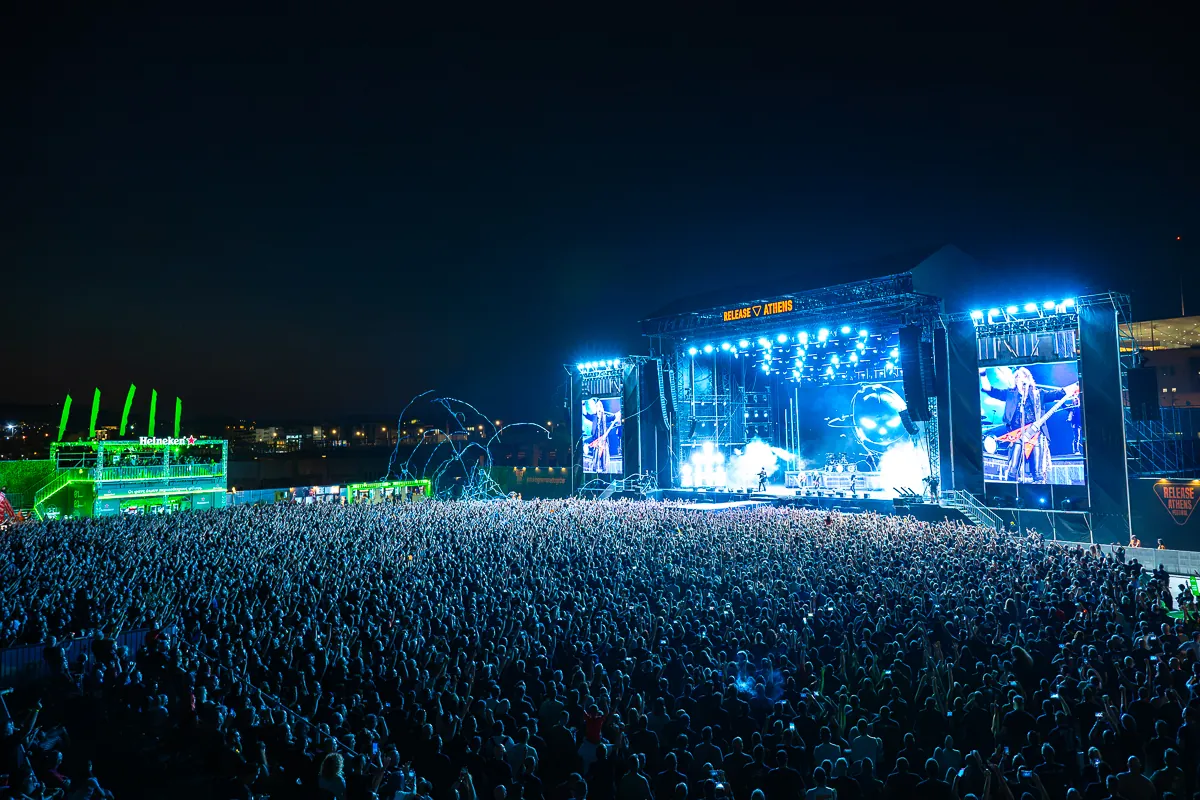 Festival main stage with big screens in front of a huge crowd at night