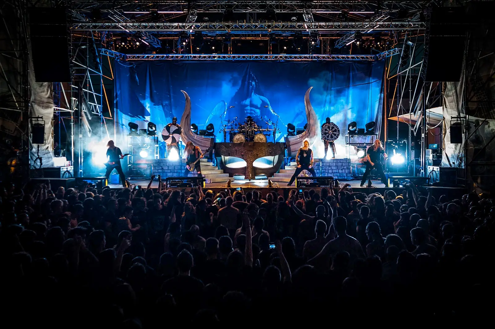 Large stage set lit in blue in front of a packed hall